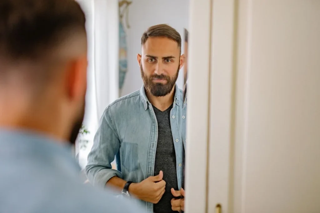 A man assessing his appearance in the mirror